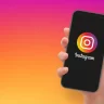 Mão segurando um smartphone com logotipo do Instagram, em formato vetorial