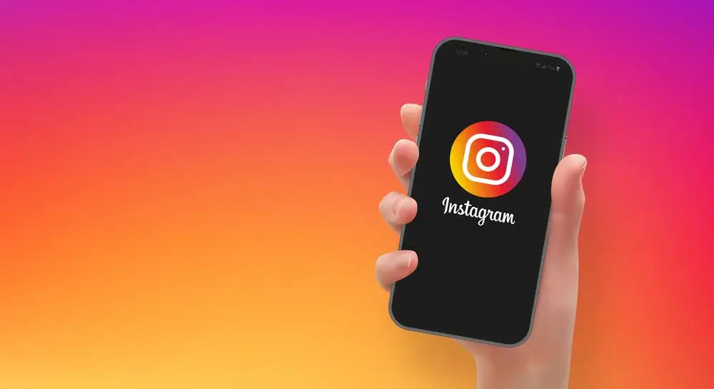 Mão segurando um smartphone com logotipo do Instagram, em formato vetorial 